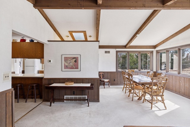 dining room with visible vents, carpet floors, vaulted ceiling with beams, and wainscoting