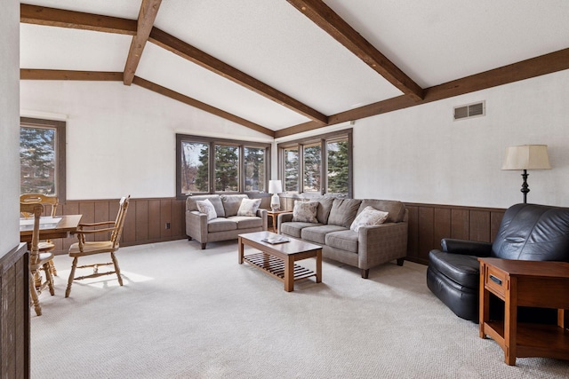 living area with visible vents, wainscoting, light colored carpet, and a healthy amount of sunlight
