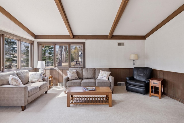 living area with vaulted ceiling with beams, visible vents, a wainscoted wall, and light carpet