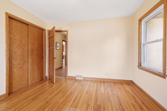 unfurnished bedroom with a closet, visible vents, baseboards, and light wood-style floors