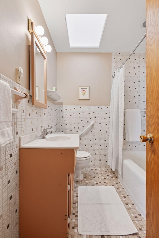 full bath with vanity, a wainscoted wall, shower / bath combo, tile walls, and toilet