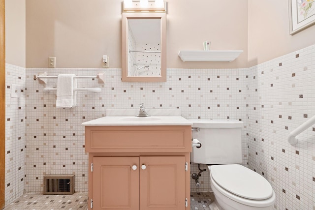 bathroom with vanity, tile walls, toilet, and visible vents