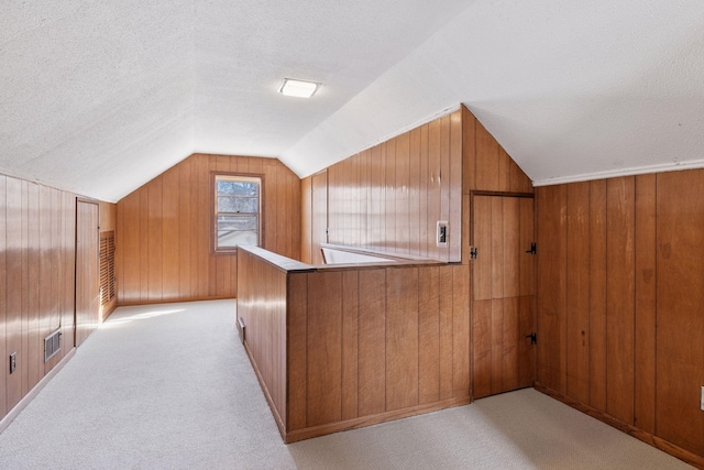 additional living space with lofted ceiling, light colored carpet, and a textured ceiling