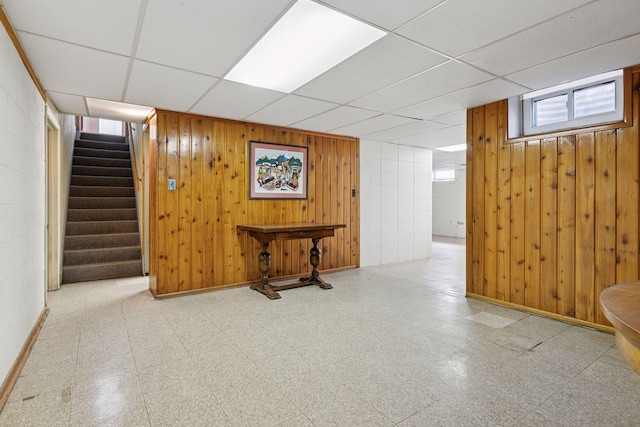 basement with tile patterned floors, stairway, a paneled ceiling, and baseboards