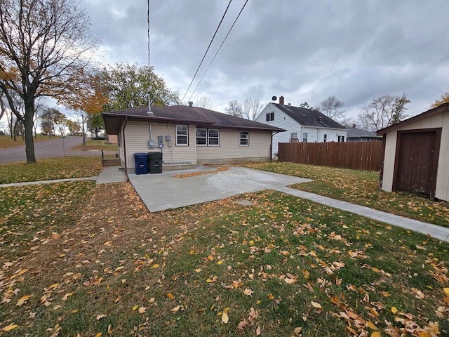 rear view of property with a storage shed, a yard, and a patio area