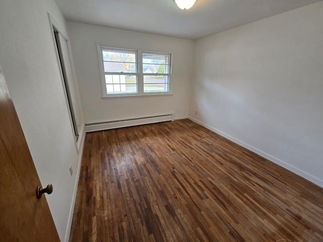 spare room with a baseboard heating unit and dark hardwood / wood-style flooring