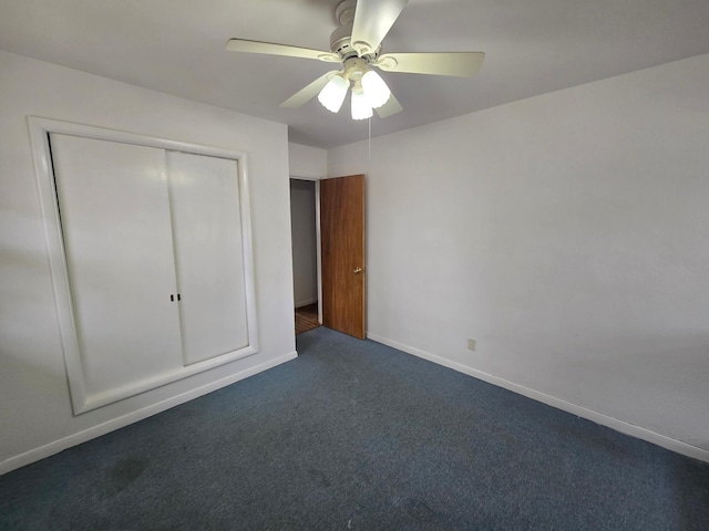 unfurnished bedroom featuring ceiling fan, a closet, and dark carpet