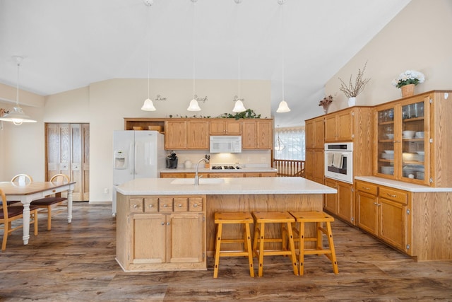 kitchen featuring white appliances, dark wood-type flooring, sink, hanging light fixtures, and an island with sink