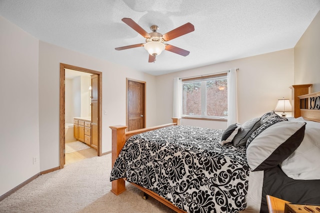 bedroom with ceiling fan, light colored carpet, a textured ceiling, and ensuite bath