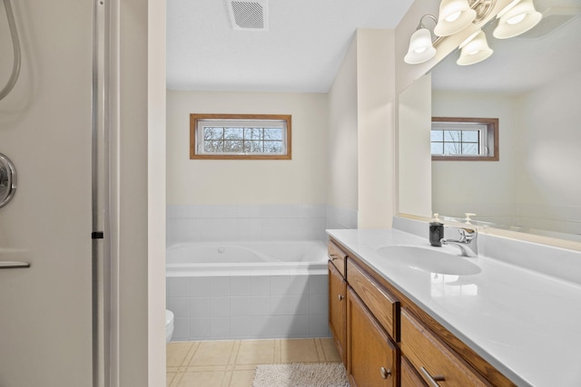 bathroom with vanity, toilet, and tiled tub