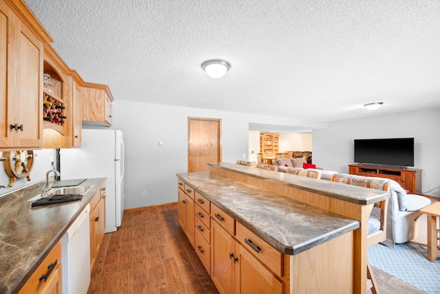 kitchen featuring light brown cabinets, sink, dark hardwood / wood-style floors, white appliances, and a breakfast bar area