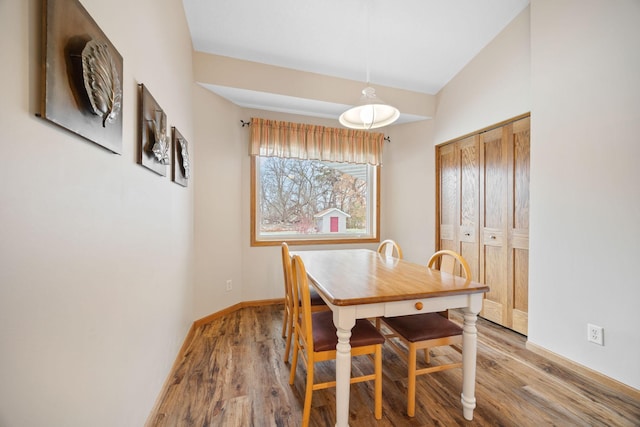 dining area with light wood-style flooring, baseboards, and vaulted ceiling