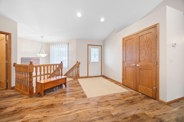 entrance foyer featuring baseboards, wood finished floors, and vaulted ceiling