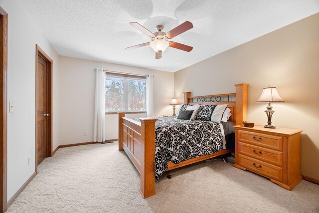 bedroom with baseboards, light carpet, and a textured ceiling