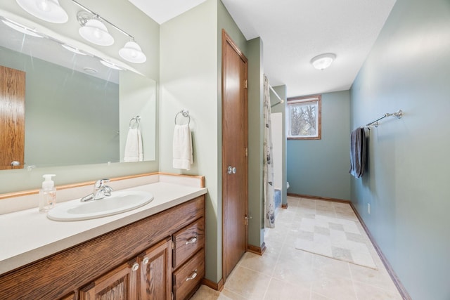 bathroom featuring vanity, a shower with shower curtain, toilet, and baseboards