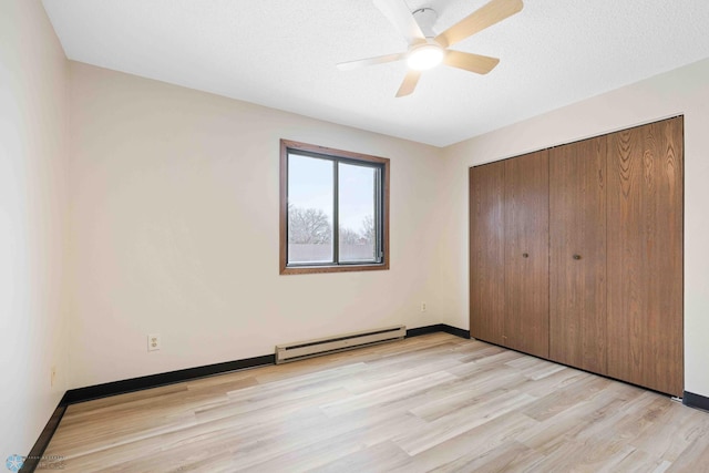 unfurnished bedroom featuring a baseboard radiator, light hardwood / wood-style floors, a textured ceiling, ceiling fan, and a closet