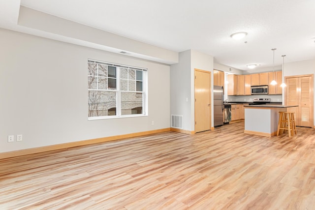 kitchen with appliances with stainless steel finishes, light hardwood / wood-style flooring, hanging light fixtures, a breakfast bar, and a center island