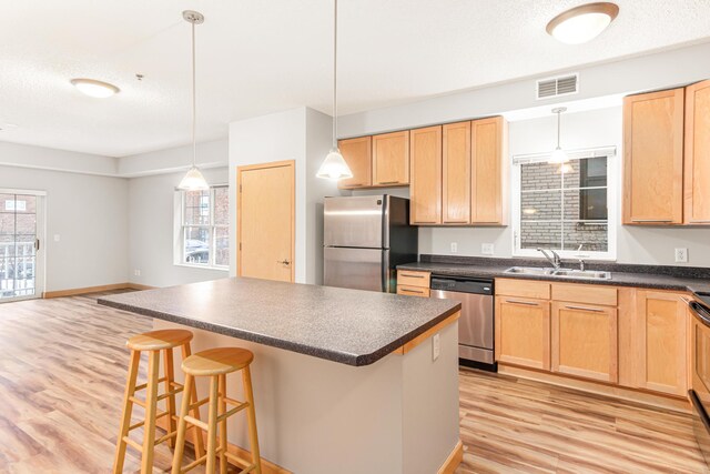 kitchen featuring light hardwood / wood-style floors, hanging light fixtures, sink, a breakfast bar, and appliances with stainless steel finishes