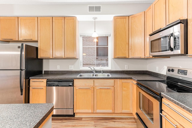 kitchen featuring stainless steel appliances, hanging light fixtures, sink, light hardwood / wood-style flooring, and light brown cabinetry