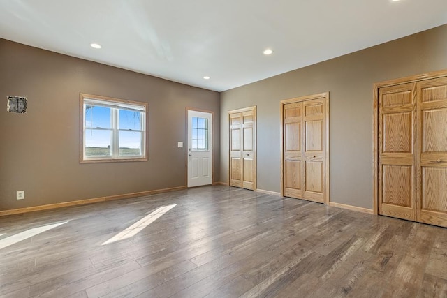 unfurnished bedroom featuring wood-type flooring and multiple closets