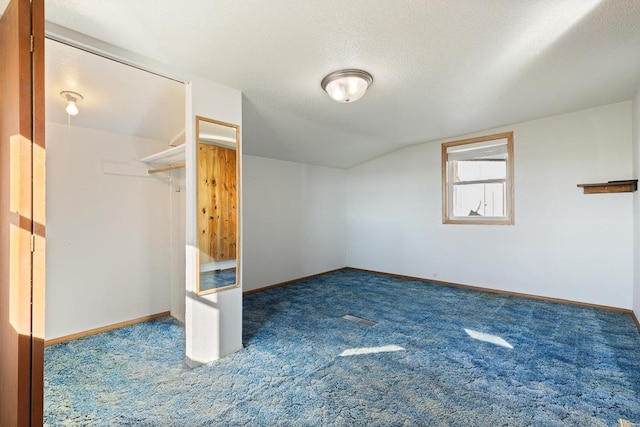 additional living space featuring dark colored carpet and a textured ceiling