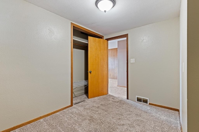 unfurnished bedroom with a closet, a textured ceiling, and carpet floors