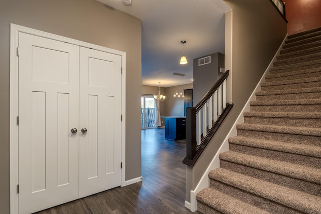 stairs with a chandelier and hardwood / wood-style flooring