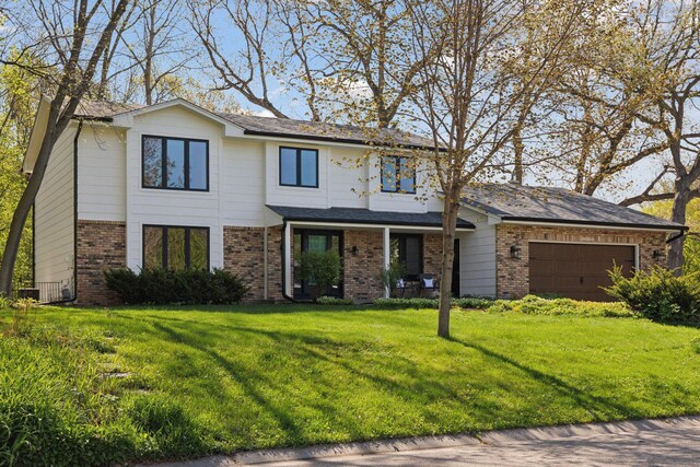 view of front facade featuring a garage, a front yard, and brick siding