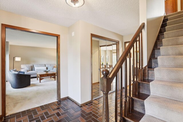 interior space featuring brick floor, a textured ceiling, and baseboards