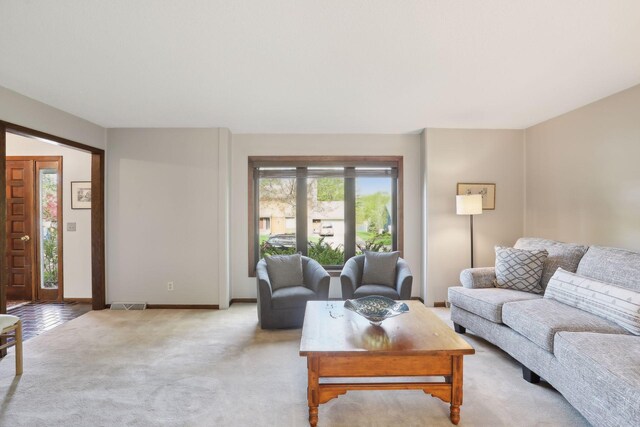 living area with light colored carpet, visible vents, and baseboards