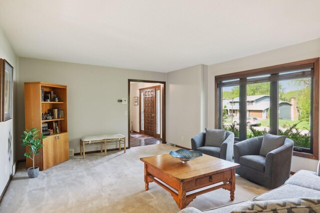 living area featuring light colored carpet, visible vents, and baseboards