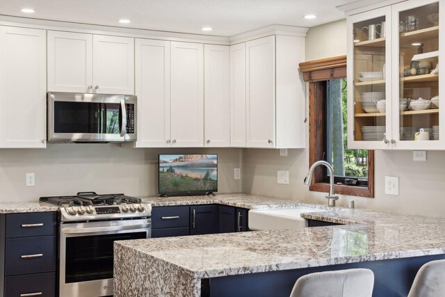 kitchen with stainless steel appliances, a kitchen bar, glass insert cabinets, and white cabinets