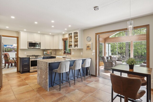 kitchen with decorative light fixtures, appliances with stainless steel finishes, glass insert cabinets, a peninsula, and a kitchen breakfast bar