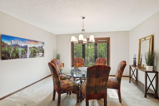 dining space featuring a textured ceiling, an inviting chandelier, baseboards, and light colored carpet