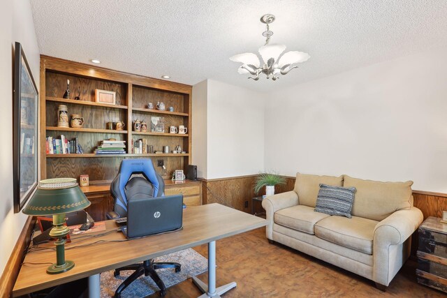 office featuring a textured ceiling, wainscoting, a chandelier, and wooden walls