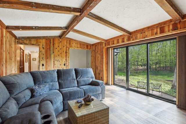 living room with vaulted ceiling with beams, light wood finished floors, and wooden walls