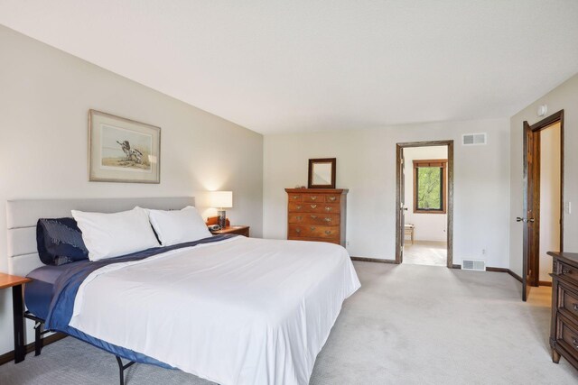 bedroom with visible vents, light carpet, baseboards, and ensuite bathroom