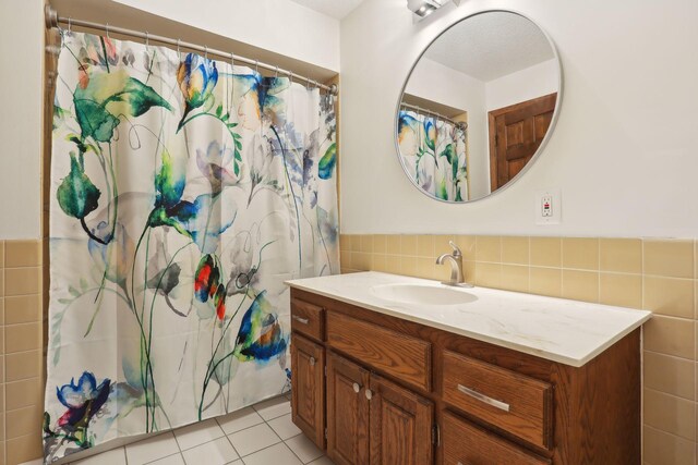 bathroom with a wainscoted wall, vanity, tile walls, and tile patterned floors