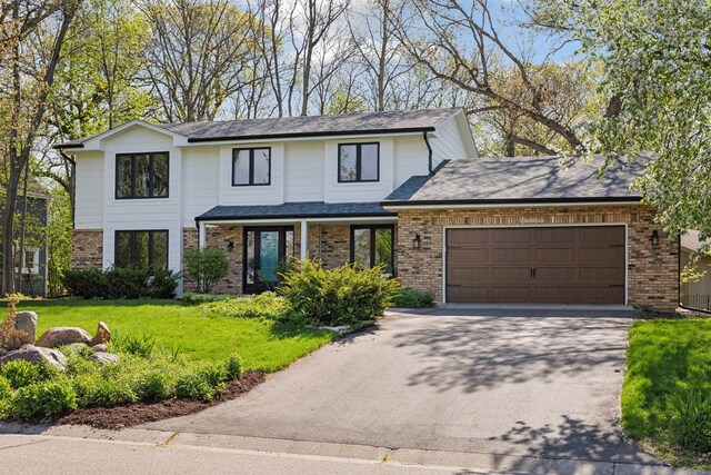 view of front facade with an attached garage, a front yard, aphalt driveway, and brick siding