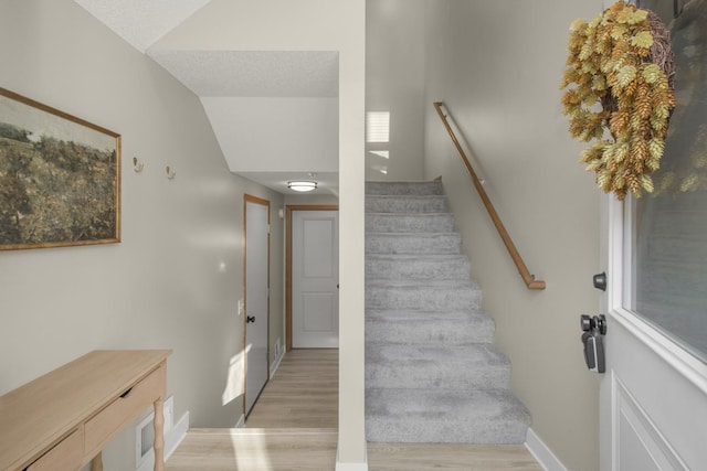 staircase featuring hardwood / wood-style flooring and lofted ceiling