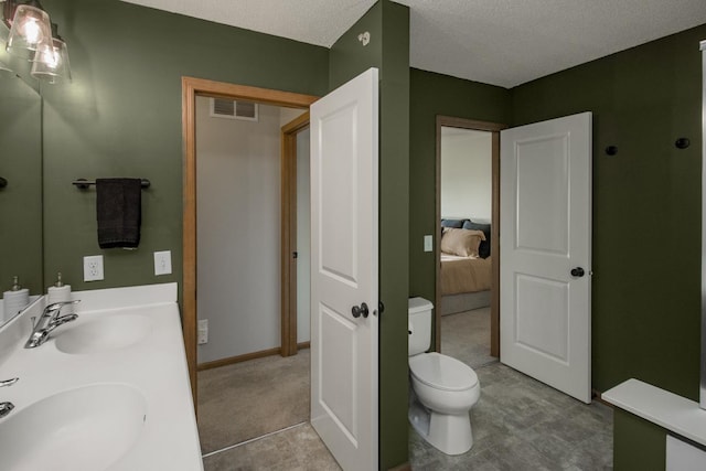 bathroom featuring vanity, toilet, and a textured ceiling