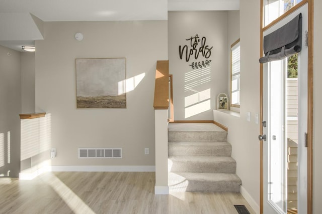 stairs with visible vents, baseboards, and wood finished floors