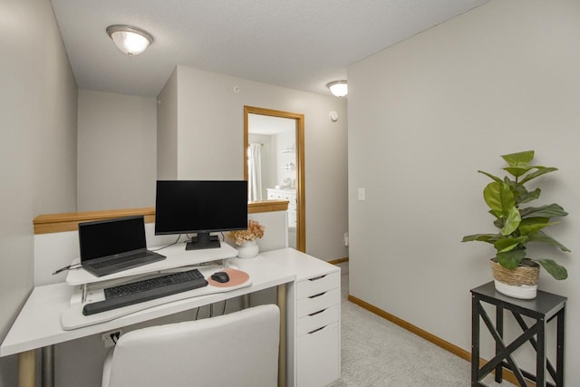 office area featuring baseboards, a textured ceiling, and light colored carpet