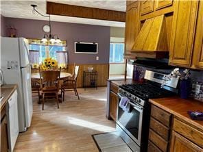 kitchen featuring an inviting chandelier, light hardwood / wood-style flooring, white appliances, decorative light fixtures, and premium range hood