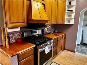 kitchen featuring gas stove, custom range hood, and light hardwood / wood-style floors