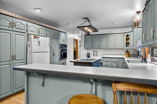 kitchen with sink, light hardwood / wood-style flooring, black appliances, a kitchen bar, and kitchen peninsula