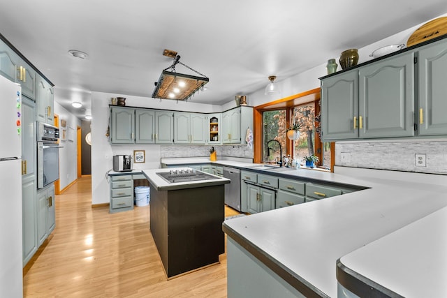 kitchen featuring sink, light hardwood / wood-style flooring, tasteful backsplash, a kitchen island, and oven