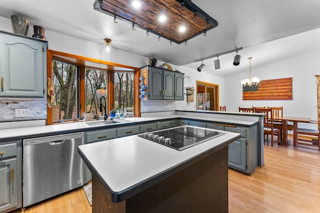 kitchen with black electric cooktop, stainless steel dishwasher, a center island, and decorative backsplash