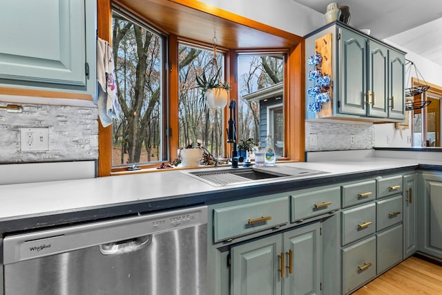 kitchen featuring stainless steel dishwasher, light hardwood / wood-style floors, and backsplash