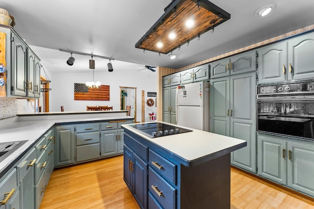 kitchen with tasteful backsplash, hanging light fixtures, black appliances, and light hardwood / wood-style floors